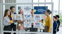 Diverse business team collaborating on global transformation strategy with colorful charts and diagrams in modern office meeting room.