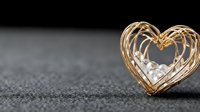 Golden wire heart shape with sparkling lights on dark textured surface for romantic Valentine's Day celebration and love concept designs.