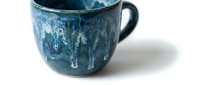 Rustic blue ceramic mug with distressed glaze finish and weathered texture, isolated on white background for design and product mockup use.