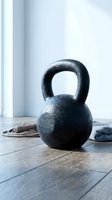 Cast iron kettlebell weight on wooden floor in bright gym studio with rope and towel, suitable for fitness training and strength workout content.