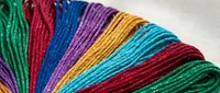 Colorful embroidery thread skeins arranged in rainbow spectrum showing vibrant cotton floss for needlework, cross stitch, and handicraft projects.