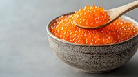 Fresh red caviar in ceramic bowl with wooden spoon, bright orange salmon roe on gray background, gourmet seafood delicacy for luxury dining.