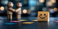 Cheerful yellow sticky note with smiley face on dark background with wooden figures and bokeh lights creating positive atmosphere for business communication.
