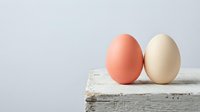 Two colored eggs on rustic wooden surface against neutral background for Easter celebration and spring holiday decoration concepts.