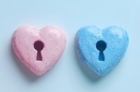 Pink and blue heart shapes with keyholes on light background symbolize romance, gender reveal concepts, and relationship connection. Minimal composition.