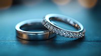 Platinum wedding bands with diamonds on turquoise background, one plain band and one eternity ring with brilliant cut stones in macro photography.