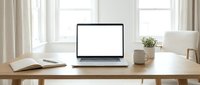 Laptop with blank screen on wooden desk in bright home office workspace with open book, coffee mug, and plant for remote work and business projects.