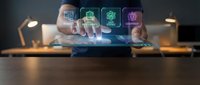 Businessman using tablet with floating holographic technology icons including AI, cloud computing, and digital innovation symbols on modern desk.