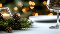 Festive winter table setting with pine branches, pinecones, wine glass and soft bokeh lights creating cozy holiday atmosphere. Perfect for seasonal menus.