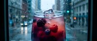 Berry cocktail with ice in a glass on a rainy city window background, blurred urban street with bokeh lights, refreshing summer drink concept.