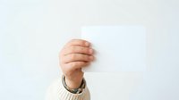Adult male hand holding blank white card or paper against neutral background, suitable for business messaging, advertising copy, promotional content, and corporate communications.
