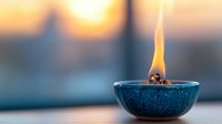 Burning candle in blue ceramic bowl against blurred sunset window background creates peaceful meditation atmosphere for spa and wellness centers.