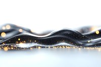 Flowing black liquid wave with golden glitter and bokeh lights on white background, creating elegant abstract macro photography effect for luxury designs.