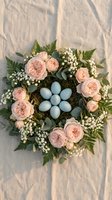 Easter wreath with pink roses, blue eggs and baby's breath on rustic wooden background for spring holiday decoration and seasonal crafts.