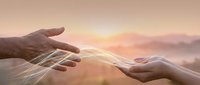 Two hands reaching toward each other with glowing light streams connecting them against soft sunset sky, symbolizing connection, unity and spiritual bond.