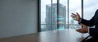 Business professional presenting holographic data analytics in modern office conference room with city skyline view for corporate presentations.
