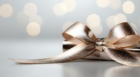 Elegant metallic rose gold ribbon bow with soft bokeh lights in background on light gray surface, festive gift wrapping and holiday decoration element.