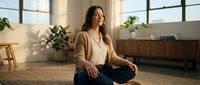 Young Hispanic woman practicing mindfulness meditation in modern living room with natural sunlight and plants for wellness and mental health.