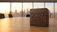 Wooden block with 2027 trends text on office desk with blurred city skyline at sunset, business forecasting and future planning concept for corporate strategy.