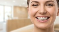 Young Caucasian woman with metal braces smiling confidently at dental clinic, showing orthodontic treatment progress for teeth straightening care.