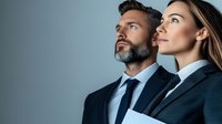 Confident business professionals in formal suits looking up with determination and aspiration, representing leadership and corporate success in modern workplace.