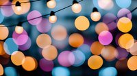 Festive bokeh lights creating magical blurred circles in pink, orange, yellow and blue tones. String lights and defocused spots form dreamy abstract background.