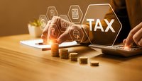 Business professional calculating taxes on laptop with digital interface icons and golden coins on wooden desk for financial planning and accounting services.