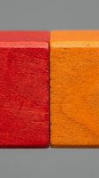Two vibrant wooden blocks in red and orange colors showcasing natural wood grain texture and craftsmanship for creative projects and design concepts.