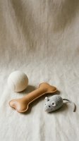 Natural leather bone toy with knitted mouse and ball on linen fabric background for pet care and playtime activities.