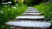 Stone path through green garden with white daisies growing alongside. Natural stepping stones create peaceful walkway in lush summer landscape.