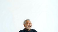 Middle-aged man with gray hair and beard, wearing dark clothing, smiling and looking upward against white background. Suitable for business, lifestyle, and portrait projects.