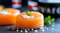 Fresh salmon fillet pieces with sea salt and herbs on dark slate, ready for gourmet cooking and culinary preparation in modern kitchen setting.