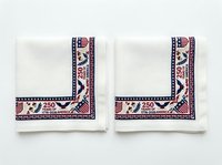 Pair of white linen napkins with patriotic navy and red geometric border trim featuring stars and stripes, isolated on white background, ready for tableware design.