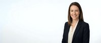 Professional businesswoman in black suit jacket smiling confidently against white background for corporate presentations and marketing materials.