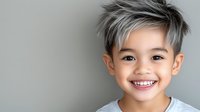 Young Asian boy with trendy silver gray hair and bright smile wearing light t-shirt against neutral background, expressing joy and confidence in modern studio portrait.