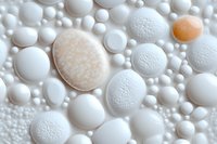 White and peach colored spheres and oval shapes with textured surfaces create abstract macro composition against light background, suggesting soap bubbles or cellular structures.