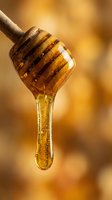 Golden honey dripping from wooden dipper stick against warm blurred background. Natural sweetener flowing in slow motion for culinary and wellness concepts.
