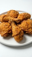 Crispy fried chicken pieces with golden-brown seasoned coating served on white plate, ready for food photography, restaurant menus, and culinary content.