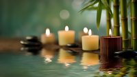 Tranquil spa setting with burning candles, bamboo stems, and hot stones reflected in calm water creating peaceful wellness atmosphere for relaxation.