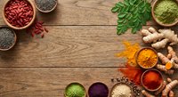 Colorful superfood ingredients arranged on rustic wooden background with goji berries, chia seeds, moringa leaves, turmeric, ginger and spices.
