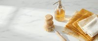 Eco-friendly bathroom accessories with natural soap dispenser, wooden brush and organic towels on marble surface for sustainable living and zero waste.
