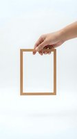 Hand holding empty wooden picture frame on white background isolated for design and presentation concepts.