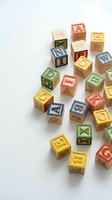 Colorful wooden alphabet blocks scattered on white background featuring letters and symbols for children's educational play and learning activities.