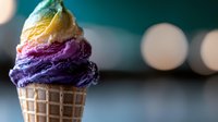 Colorful ice cream scoops stacked in waffle cone featuring vibrant purple, yellow and white flavors against blurred bokeh background, macro food photography.