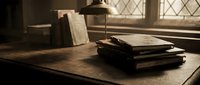 Old leather-bound books stacked on wooden desk in vintage library with warm sunlight streaming through diamond-paned windows creating atmospheric study scene.