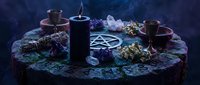 Mystical altar setup with black candle, crystals, pentagram symbol and ritual items on wooden surface for spiritual practices and witchcraft ceremonies.
