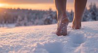 Barefoot person walking through fresh snow during golden hour sunset with warm light creating peaceful winter scene for wellness and mindfulness concepts.