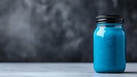 Vibrant blue smoothie or protein shake in mason jar on gray concrete background with moody atmosphere and copy space for healthy lifestyle concept.
