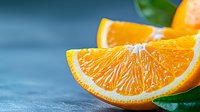 Fresh juicy orange wedges with green leaves on blue background, macro shot showing detailed pulp texture and citrus segments for food photography.