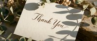 Elegant thank you card with calligraphy script surrounded by green eucalyptus leaves and soft shadows, perfect for weddings and celebrations.